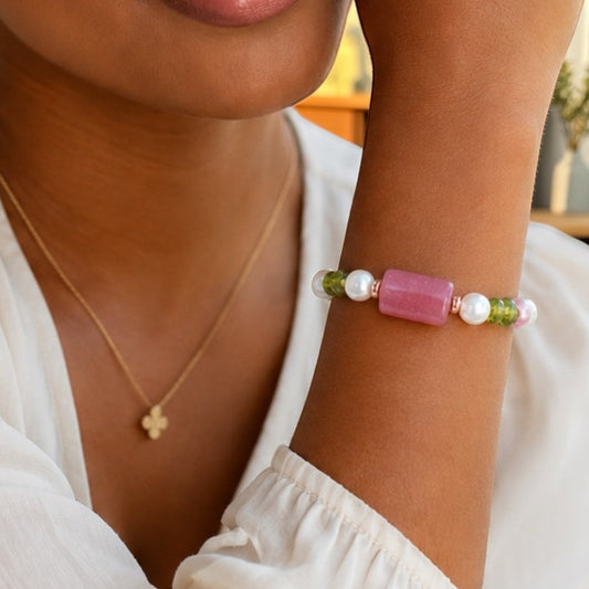 House of Lux Gifts stretch bracelet with white pearls, green peridot, and a rectangular pink gemstone on a wrist.