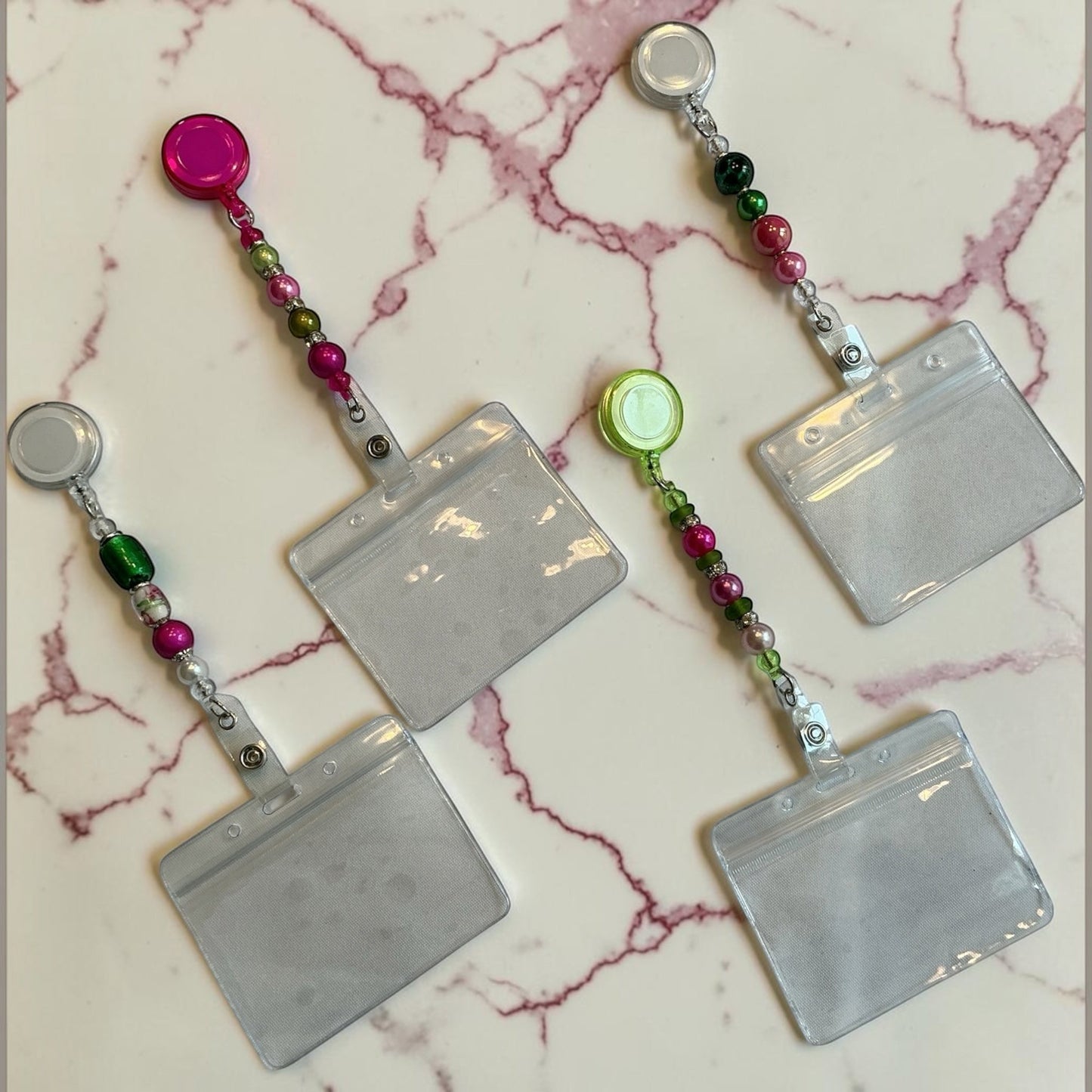 House of Lux Gifts set of four retractable ID badge lanyards featuring pink and green beaded accents on a marble surface.