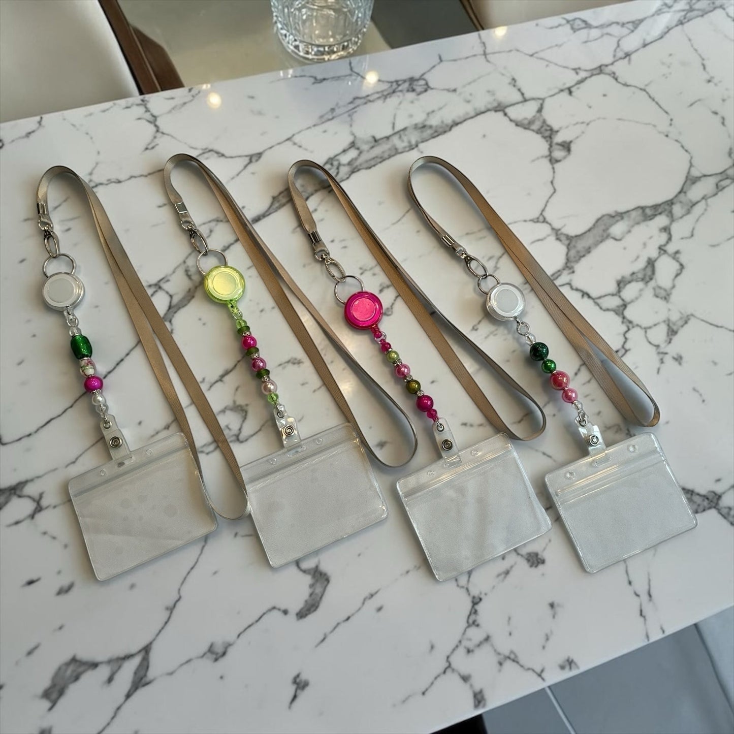 House of Lux Gifts retractable beaded ID badge lanyards in pink and green on a marble surface