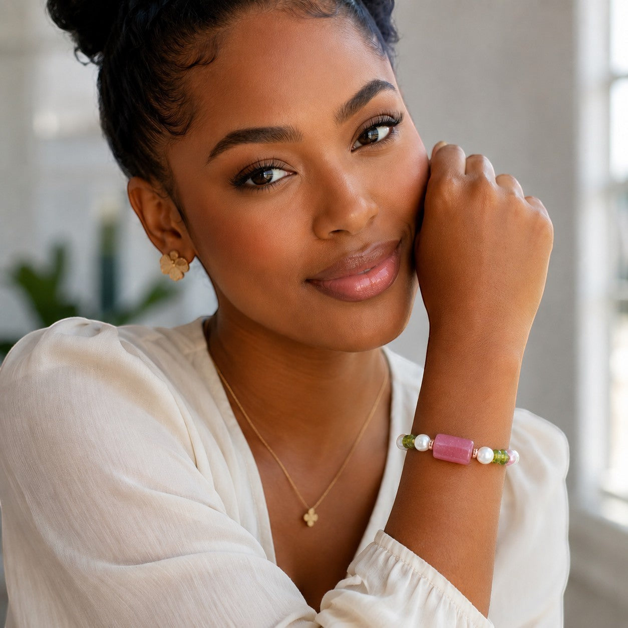 House of Lux Gifts stretch bracelet with pearls, green peridot, and a pink gemstone worn by a smiling woman.