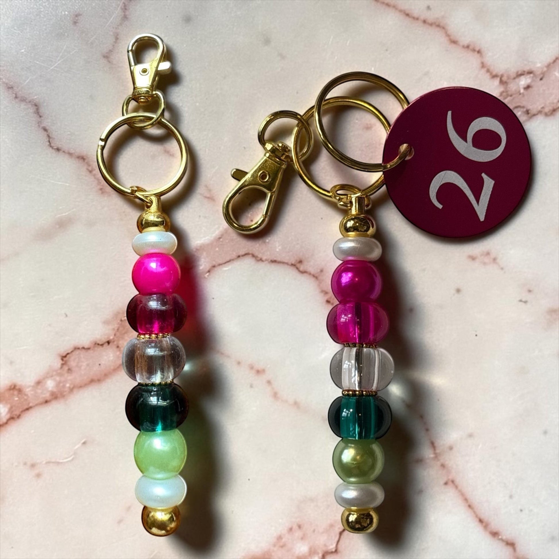 House of Lux Gifts beaded keychain with multi-colored beads in pink, clear, and green with gold-tone hardware.
