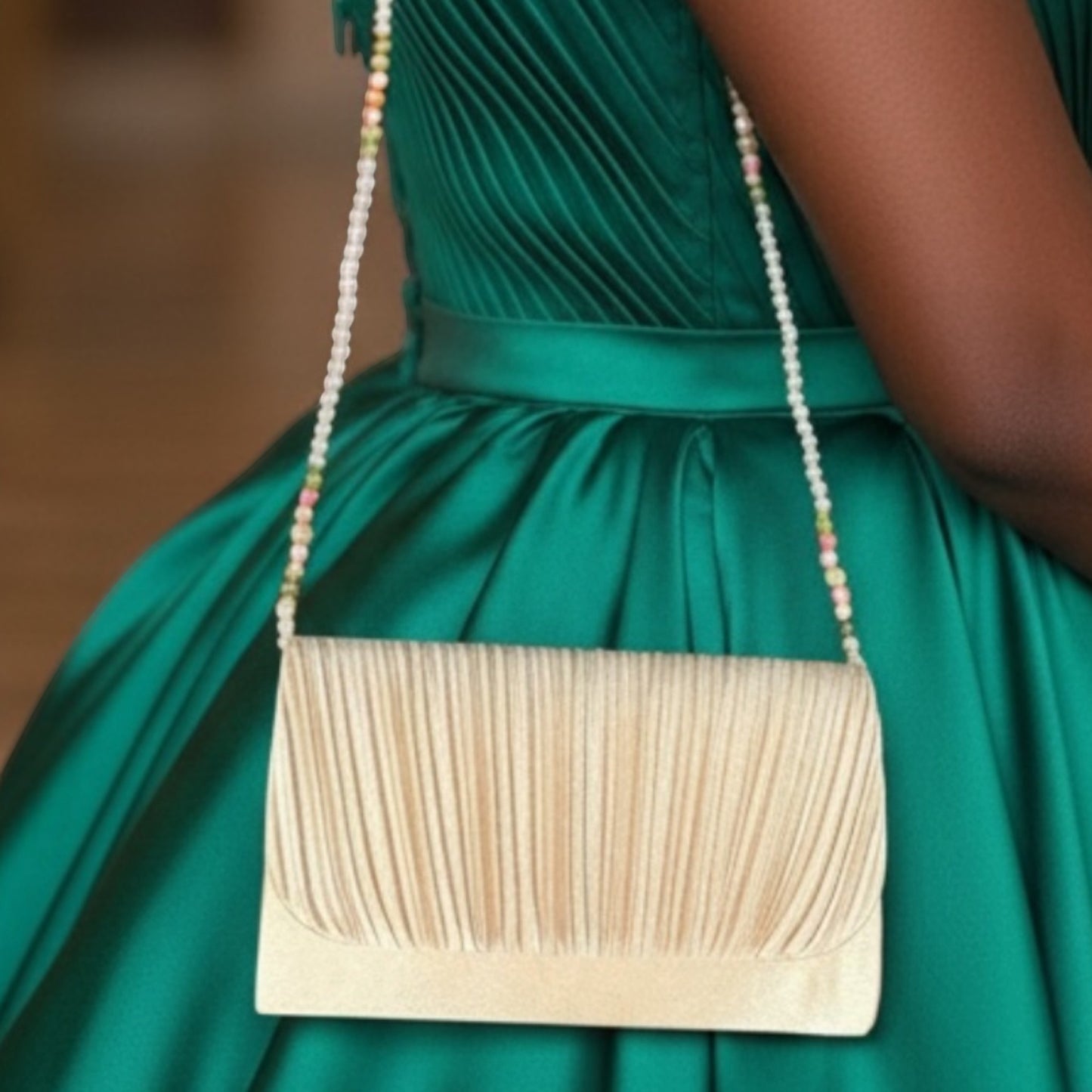 House of Lux Gifts cream pleated evening clutch with a beaded shoulder strap worn against a green satin dress