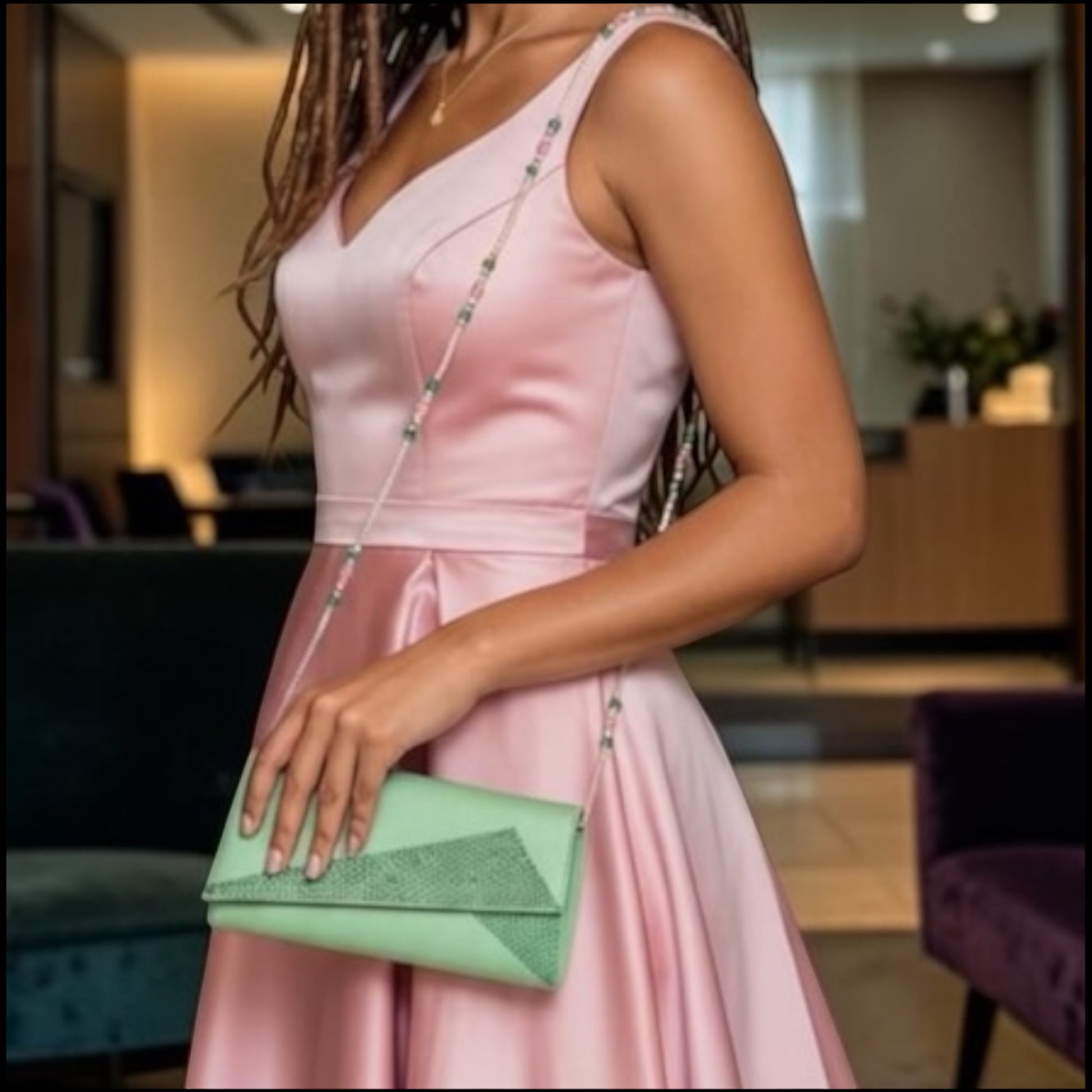 House of Lux Gifts green crystal evening clutch with beaded strap worn by a woman in a pink satin formal dress.