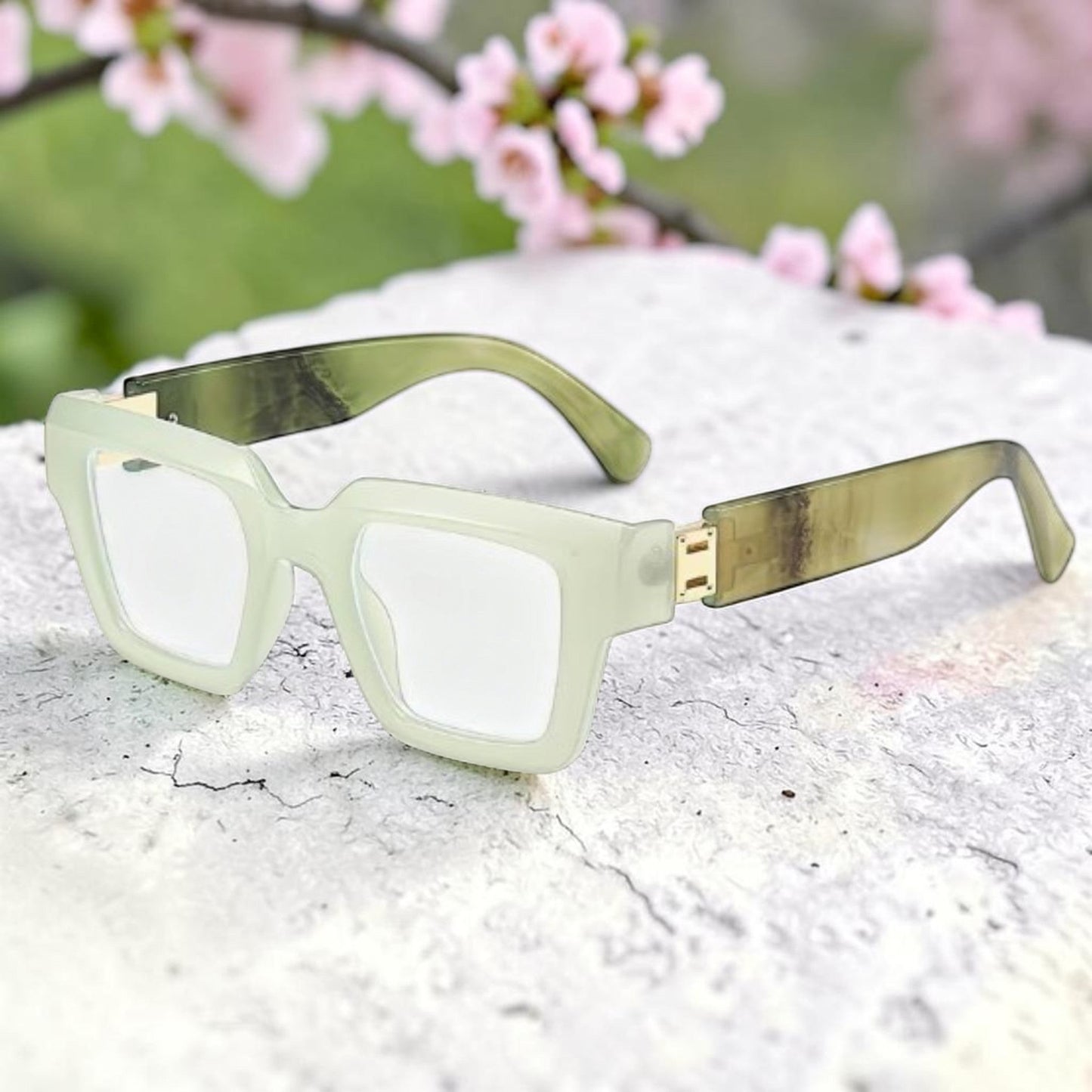 House of Lux Gifts light and dark green square frame reader glasses with gold accents resting on a stone surface