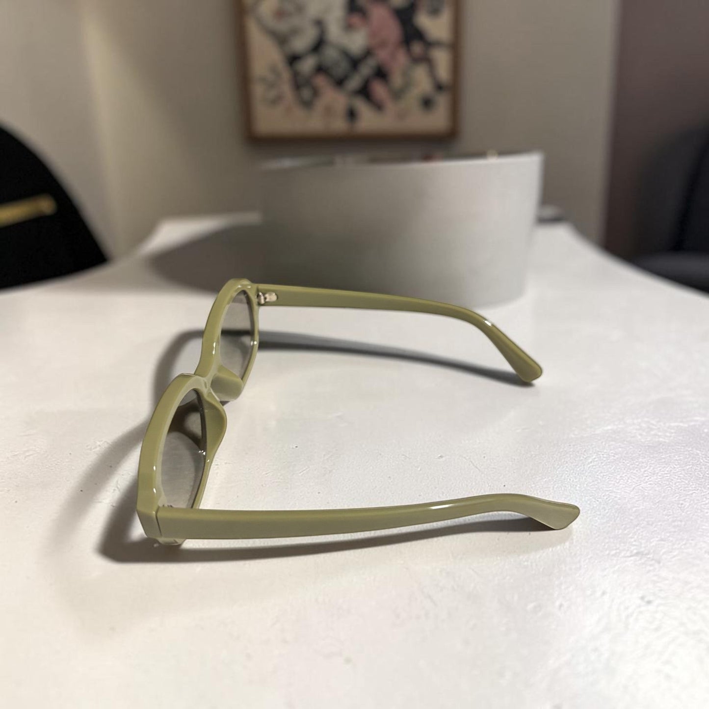House of Lux Gifts olive green sunglasses with a sleek rectangular frame resting on a white surface