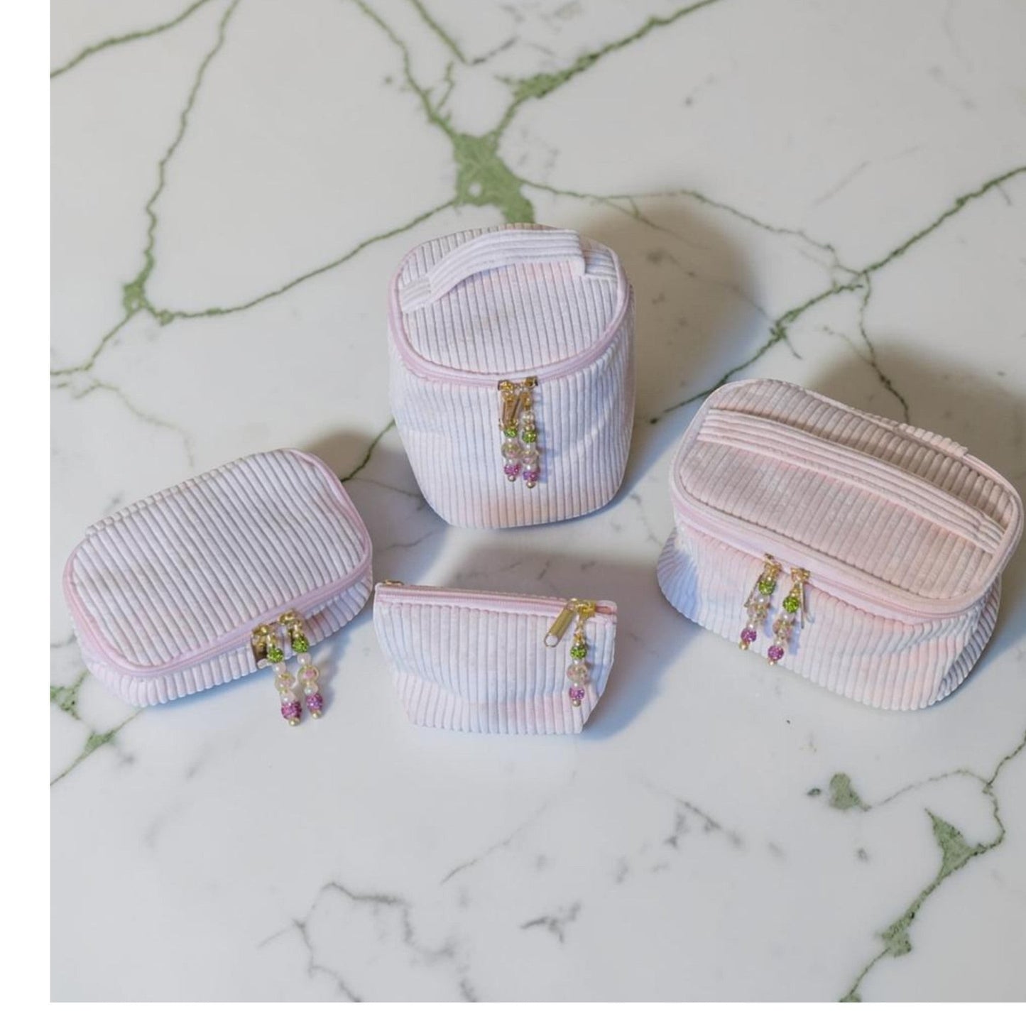 House of Lux Gifts 4-piece blush pink corduroy cosmetic bag set with beaded zipper pulls on a marble surface.