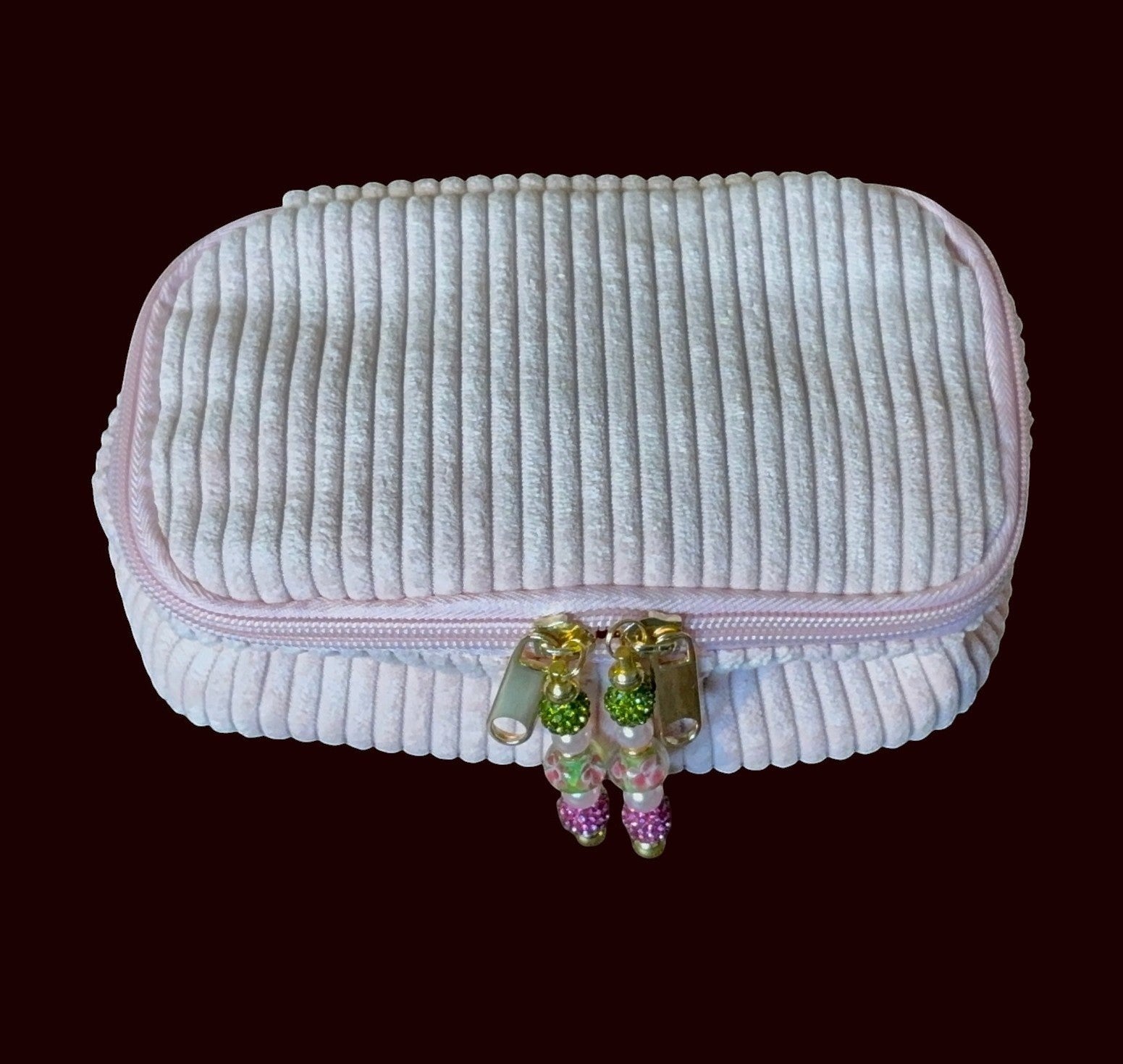 House of Lux Gifts blush pink ribbed corduroy cosmetic bag with gold zipper and decorative beaded pulls.