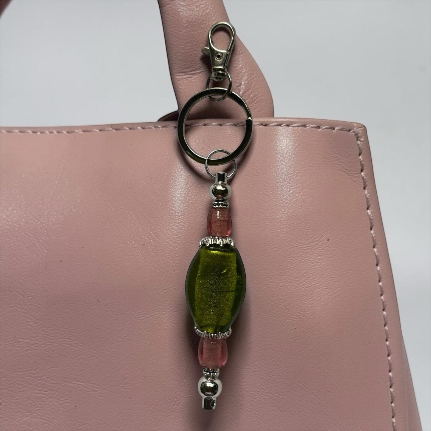 House of Lux Gifts handmade lampwork glass bag charm with green statement bead, pink accents, and gold-plated metal.