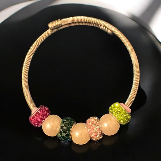 House of Lux Gifts handmade bangle bracelet with pink and green rhinestone beads and faux pearls on a gold wire band.