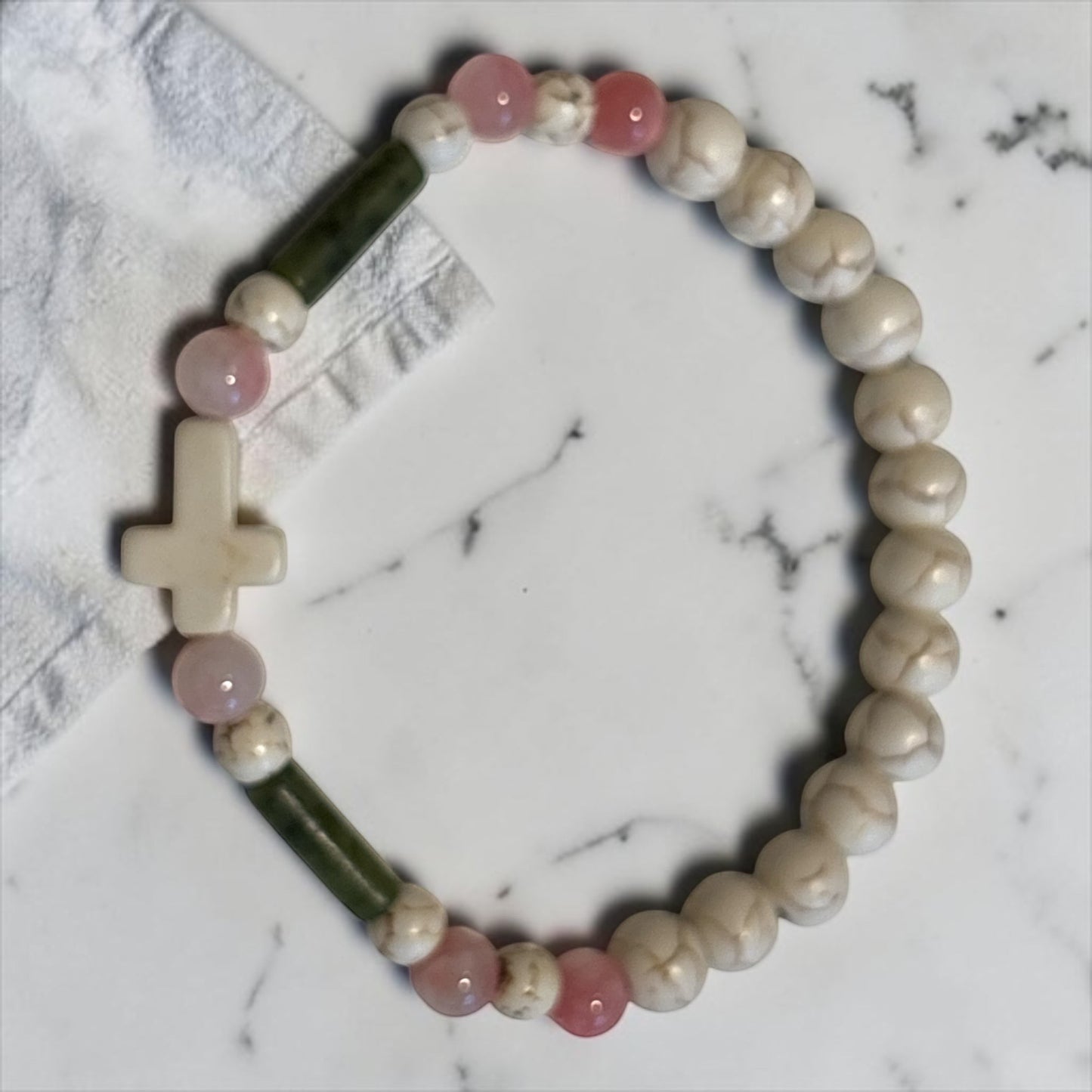 House of Lux Gifts handmade stretch bracelet featuring white turquoise beads, pink and green jade, and a cross charm.